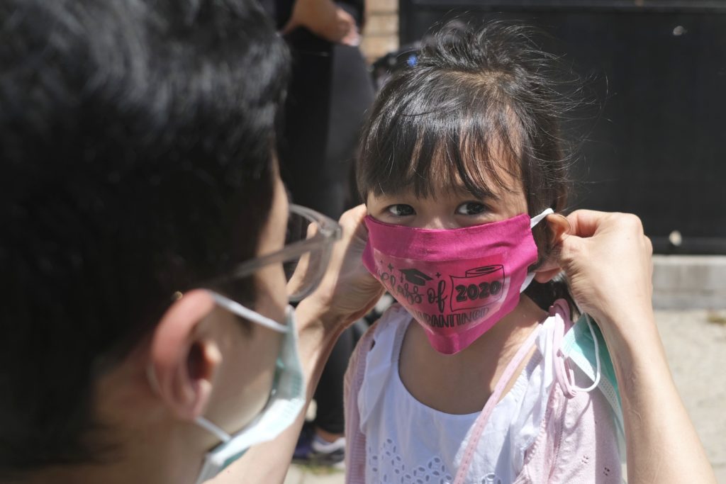 Photo of child putting on virus mask