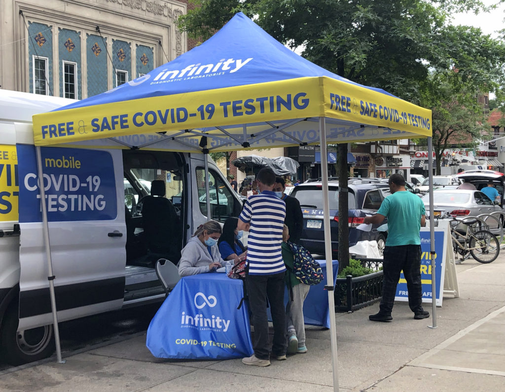 Photo of people getting covid 19 test by mobile unit on sidewalk