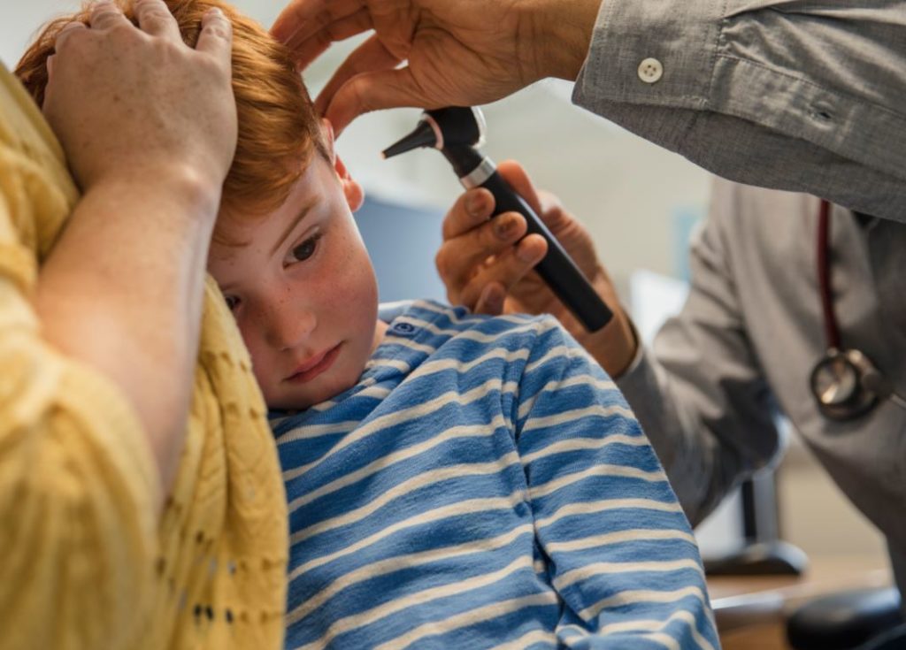 Photograph of a doctor examining a childs ear.
