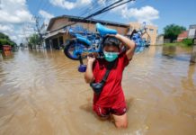 Photo of Child walking through flood waters carrying a bicycle