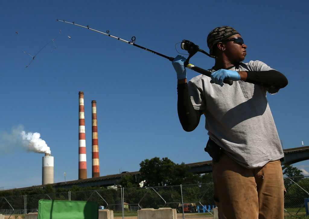 Photo of man fishing near coal-fired power plant