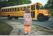 Photograph of a small child walking towards a school bus