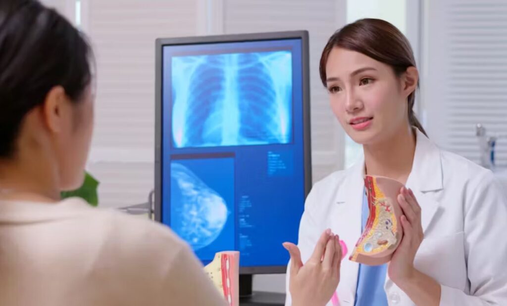 Photo of a doctor and a patient examining a model of a human breast.