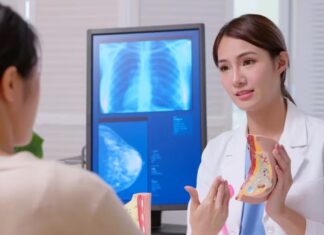 Photo of a doctor and a patient examining a model of a human breast.