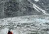 Photo of researcher descending into empty glacial valley.