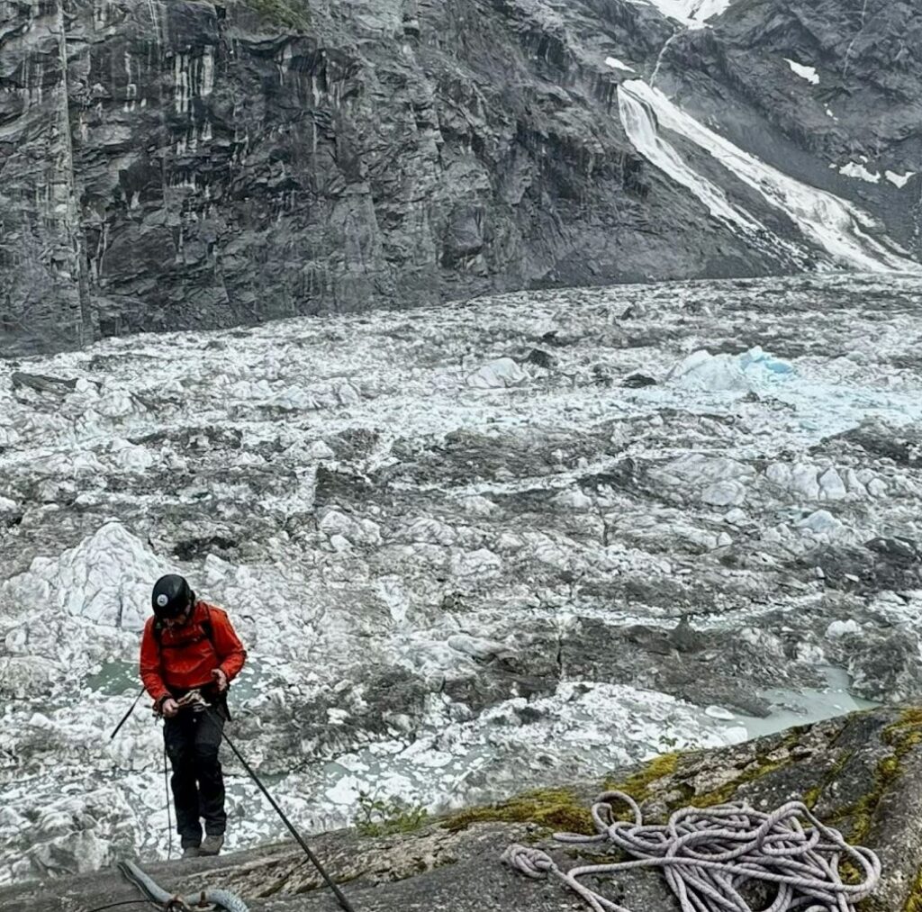 Photo of researcher descending into empty glacial valley.