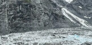 Photo of researcher descending into empty glacial valley.