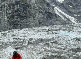 Photo of researcher descending into empty glacial valley.