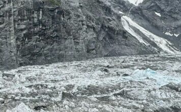 Photo of researcher descending into empty glacial valley.