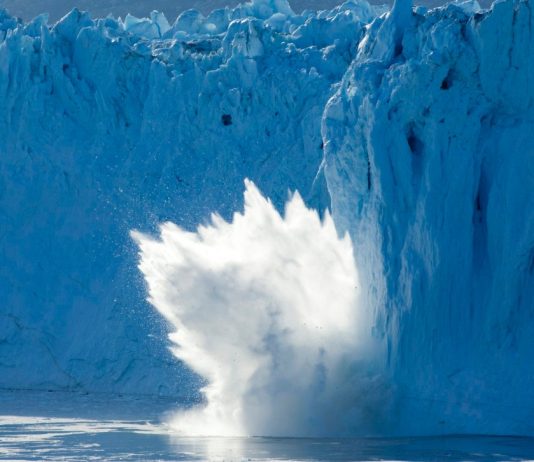 Photo of an iceberg breaking off of a glacier