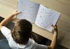 Nearly every state in the US has dyslexia laws – but our research shows limited change for struggling readers Photo of a child with dyslexia struggling to read, Letters on the page are disorganized indicating child's struggle.