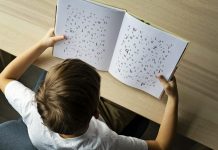 Photo of a child with dyslexia struggling to read, Letters on the page are disorganized indicating child's struggle.