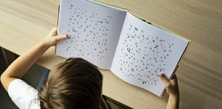Photo of a child with dyslexia struggling to read, Letters on the page are disorganized indicating child's struggle.