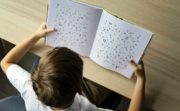 Photo of a child with dyslexia struggling to read, Letters on the page are disorganized indicating child's struggle.