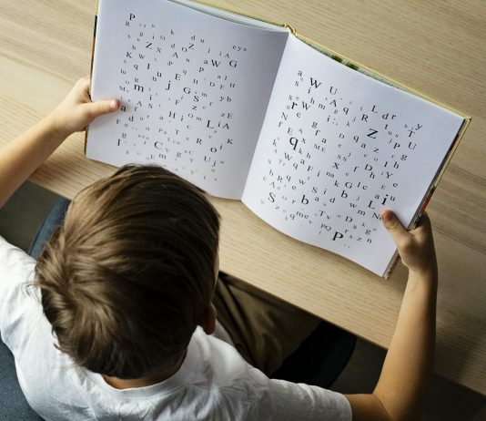 Photo of a child with dyslexia struggling to read, Letters on the page are disorganized indicating child's struggle.
