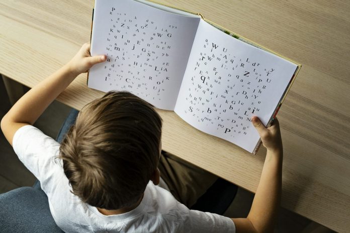Photo of a child with dyslexia struggling to read, Letters on the page are disorganized indicating child's struggle.